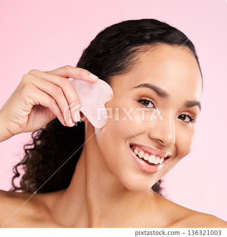 Gua sha, face massage and woman with natural beauty, skin glow and cosmetics. Portrait of a young aesthetic female model happy with self care, facial or dermatology results on a pink background Gua sha, face massage and woman with natural beauty, skin glow and cosmetics. Portrait of a young aesthetic female model happy with self care, facial or dermatology results on a pink background 136321003