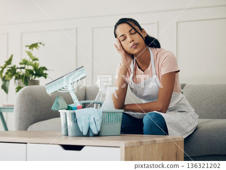 Cleaning, tired and exhausted woman in a house to clean with supplies, detergents or tools. Young female or cleaner in a lounge with headache or stress in an apartment or room with fatigue or problem 136321202