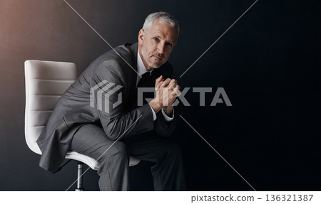 Portrait, manager or corporate with a business man sitting on a chair in studio against a dark background. Leadership, management and a senior male CEO in a professional suit for his executive career 136321387