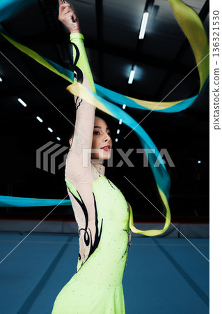 Ribbon, dance and rhythmic gymnastics, woman in gym with action and performance for fitness. Competition, athlete and female gymnast, dancer with creativity and art, routine and energy at arena Ribbon, dance and rhythmic gymnastics, woman in gym with action and performance for fitness. Competition, athlete and female gymnast, dancer with creativity and art, routine and energy at arena 136321530
