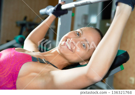 Portrait, woman and barbell press workout in gym for power, exercise and strong bodybuilding. Happy female athlete, weights and fitness training on bench for healthy muscles, sports or action in club Portrait, woman and barbell press workout in gym for power, exercise and strong bodybuilding. Happy female athlete, weights and fitness training on bench for healthy muscles, sports or action in club 136321768