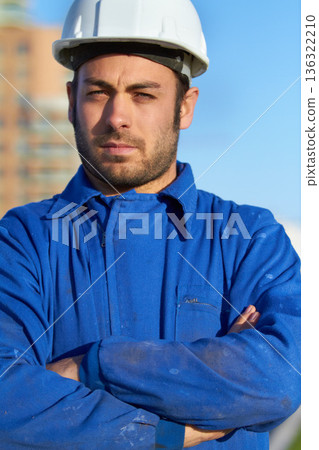 Man, architect and portrait of confident contractor with arms crossed for building construction in city. Serious male person, engineer or builder with hard hat for industrial architecture in town Man, architect and portrait of confident contractor with arms crossed for building construction in city. Serious male person, engineer or builder with hard hat for industrial architecture in town 136322210