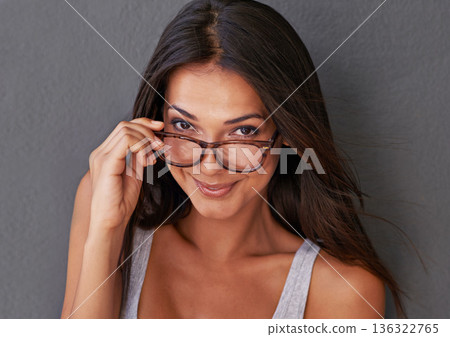 Woman is confident, looking over glasses with eye care, vision and face in fashion eyewear against wall background. Portrait, designer frame and prescription lens, sexy female model and optometry 136322765