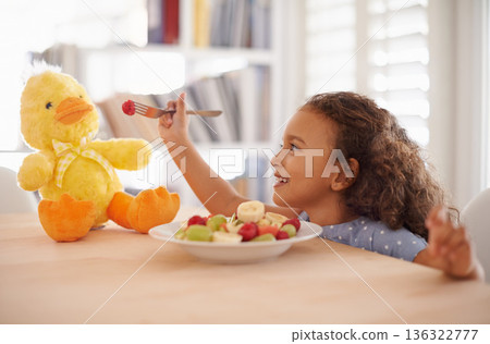 Child feeding, teddy bear and food at home with happiness and wellness meal with a smile. House, nutrition and young girl with healthy fruit salad and fruits of a hungry kid with toy duck at a table Child feeding, teddy bear and food at home with happiness and wellness meal with a smile. House, nutrition and young girl with healthy fruit salad and fruits of a hungry kid with toy duck at a table 136322777