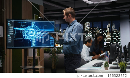 Manager in office using screen to analyze machine learning algorithms built by workers. Startup team leader supervising code written by employees to improve artificial intelligence Manager in office using screen to analyze machine learning algorithms built by workers. Startup team leader supervising code written by employees to improve artificial intelligence 136322852