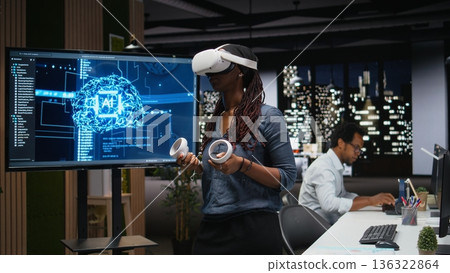 Technician in office using VR headset gear to fix bugs in artificial intelligence system. Worker troubleshooting neural network errors with virtual reality equipment in tech agency workplace 136322864