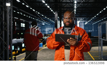 Plant staff member uses heavy tools near welding sparks on factory floor, wearing protective uniform. Manufacturing development and powerful industrial environment in workshop. Plant staff member uses heavy tools near welding sparks on factory floor, wearing protective uniform. Manufacturing development and powerful industrial environment in workshop. 136322898
