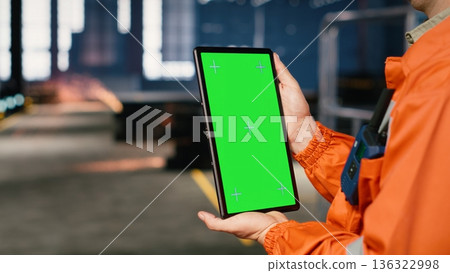 Vertical green screen with worker standing near metal tools and machinery in industry plant, using equipment to coordinate assembly duties. Structured manufacturing process. Vertical green screen with worker standing near metal tools and machinery in industry plant, using equipment to coordinate assembly duties. Structured manufacturing process. 136322998