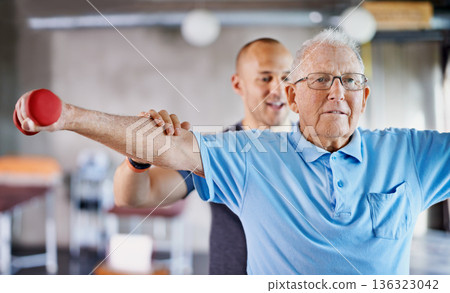 Physiotherapist, senior man and weight training for health and wellness therapy in retirement. Healthcare, physio and workout for recovery with a dumbbell for medical excuse and elderly male person Physiotherapist, senior man and weight training for health and wellness therapy in retirement. Healthcare, physio and workout for recovery with a dumbbell for medical excuse and elderly male person 136323042