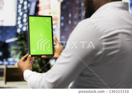 Vertical green screen with black man holding a tablet and walking downtown, enjoying a stroll near skyscrapers under city lights in the busy urban city center. Metropolitan area. Vertical green screen with black man holding a tablet and walking downtown, enjoying a stroll near skyscrapers under city lights in the busy urban city center. Metropolitan area. 136323158