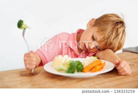 Sad, diet and a child with vegetables for dinner, unhappy meal and problem with food. Frustrated, hungry and dislike of boy kid eating broccoli, carrots and disappointed with healthy lunch at home Sad, diet and a child with vegetables for dinner, unhappy meal and problem with food. Frustrated, hungry and dislike of boy kid eating broccoli, carrots and disappointed with healthy lunch at home 136323259