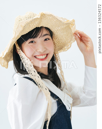 Portrait of a young woman wearing a straw hat 136324572