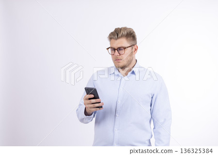 Focused young man using smartphone while looking at screen Focused young man using smartphone while looking at screen 136325384