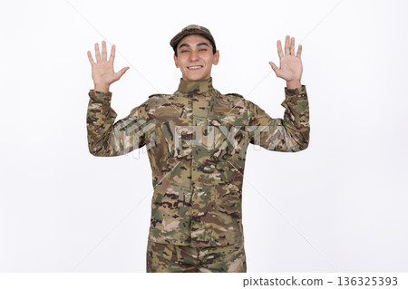 Happy soldier in camouflage raising hands in joy Happy soldier in camouflage raising hands in joy 136325393