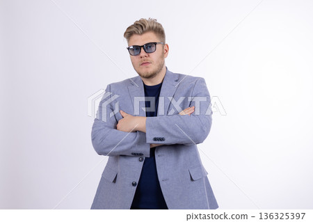 Man in grey suit and sunglasses standing with arms crossed 136325397
