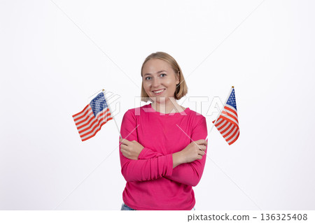 Happy woman posing with two American flags in hands 136325408