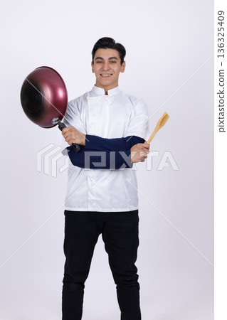 Chef holding pan and looking at it with concentration 136325409