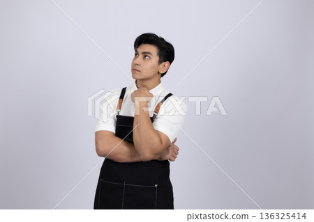 Thoughtful waiter in black apron looking away from camera Thoughtful waiter in black apron looking away from camera 136325414