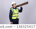 Worker carrying wooden plank on his shoulder in studio 136325417