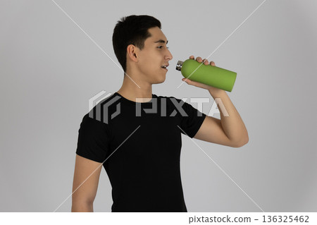 Young man drinking from a green protein shaker bottle 136325462