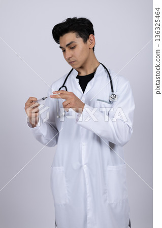 Male doctor in white coat preparing medical syringe 136325464