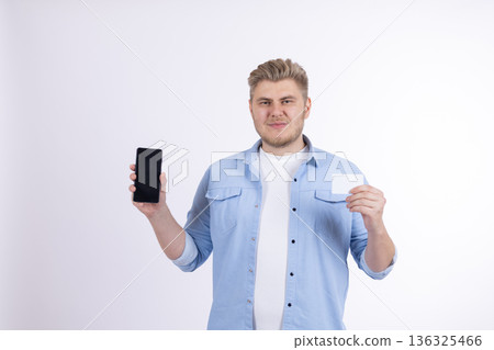 Young man showing smartphone screen and bank credit card 136325466