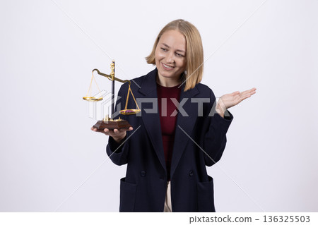 Businesswoman in suit holding justice scales in studio Businesswoman in suit holding justice scales in studio 136325503