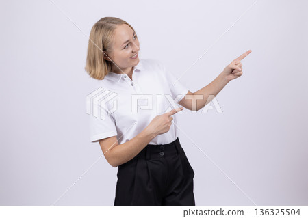 Young woman in white shirt pointing to the side Young woman in white shirt pointing to the side 136325504