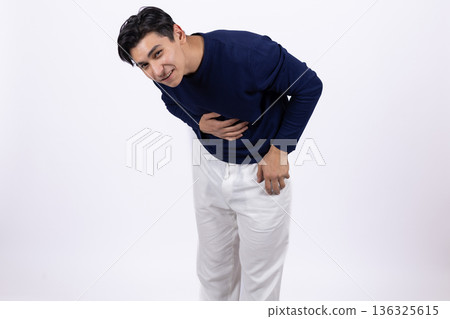 Young man in blue sweater holding his stomach and laughing 136325615