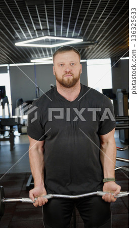 Man holding barbell standing in fitness club Man holding barbell standing in fitness club 136325633