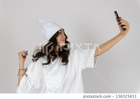 Smiling woman taking selfie with clean laundry stack 136325651