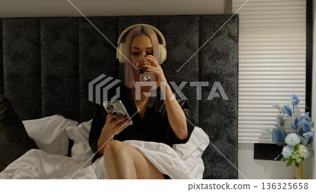 Woman relaxing in bed while listening to music Woman relaxing in bed while listening to music 136325658
