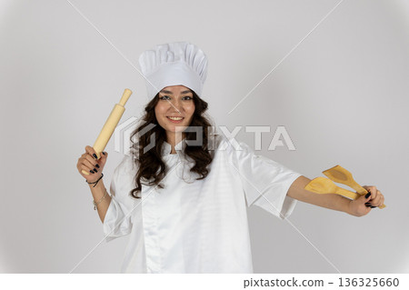 Female chef posing with rolling pin and spatula Female chef posing with rolling pin and spatula 136325660