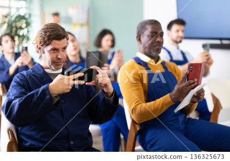 Middle aged man worker take photos of presentation slide or scan QR code in classroom 136325673