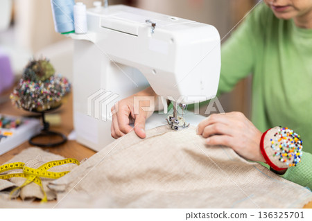 Closeup of woman hands and sewing machine - process of making clothes 136325701