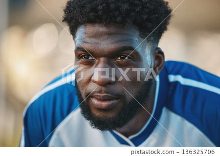 Soccer player, thinking or tired black man in sports training, game or match breathing on a field pitch. Face, fatigue or exhausted African athlete in football workout or fitness exercise on break 136325706