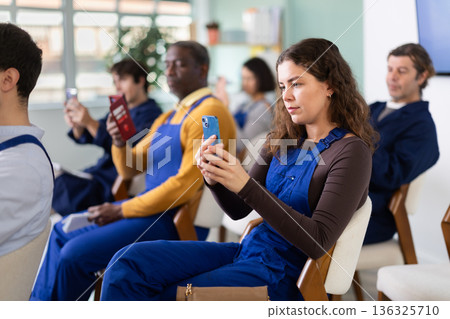 Young woman worker takes photo or scans QR code with mobile phone 136325710