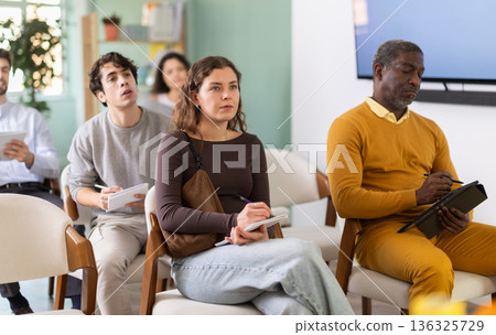 During lecture meeting, young woman pupil listen to teacher, write down summary. During lecture meeting, young woman pupil listen to teacher, write down summary. 136325729