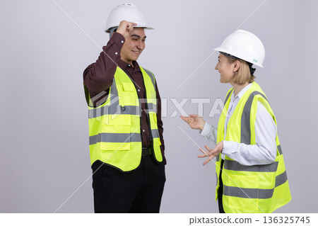 Two construction workers in safety vests talking together Two construction workers in safety vests talking together 136325745