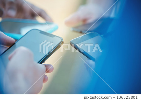Hands, phone and networking with people in a huddle or circle for communication or connectivity. Mobile, social media or information sharing and a person group standing together closeup with flare Hands, phone and networking with people in a huddle or circle for communication or connectivity. Mobile, social media or information sharing and a person group standing together closeup with flare 136325801