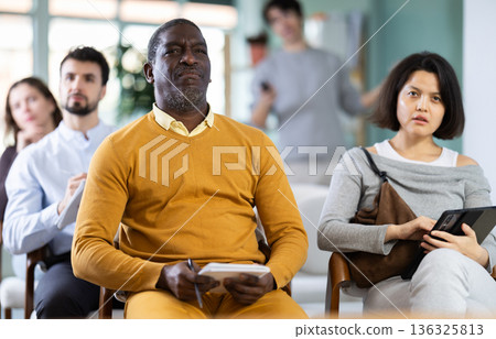 Portrait of an attentive man in linguistics class, taking notes in notebook 136325813