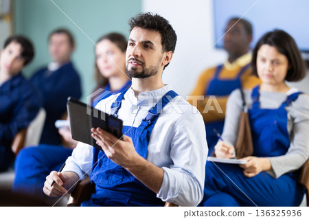 Young man worker listening to lecture and taking notes on tablet Young man worker listening to lecture and taking notes on tablet 136325936