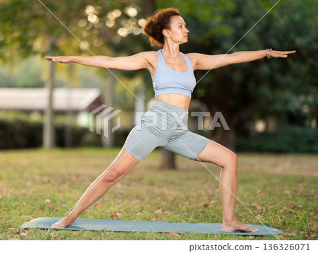 Adult woman doing yoga in warrior pose Adult woman doing yoga in warrior pose 136326071