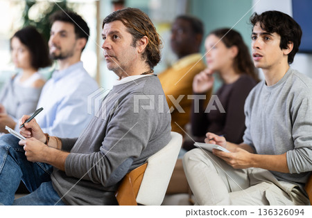 During lecture meeting, middle aged man pupil listen to teacher, write down summary. During lecture meeting, middle aged man pupil listen to teacher, write down summary. 136326094