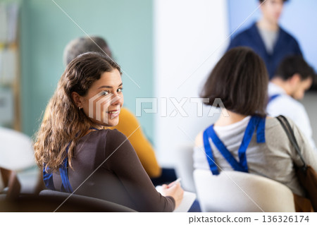 Young woman worker listens and takes notes in lecture hall Young woman worker listens and takes notes in lecture hall 136326174