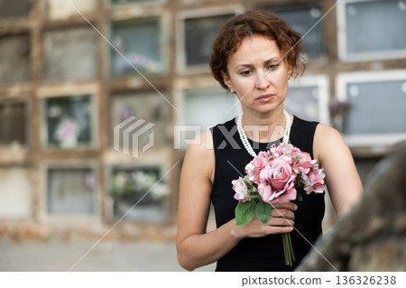 Woman brought flowers to the cemetery and cries over the death of beloved relative 136326238
