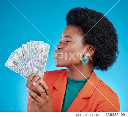 Cash, kiss and a black woman lottery winner on a blue background in studio holding money for finance. Savings, investment or economy growth with a young female person posing for financial freedom Cash, kiss and a black woman lottery winner on a blue background in studio holding money for finance. Savings, investment or economy growth with a young female person posing for financial freedom 136326409