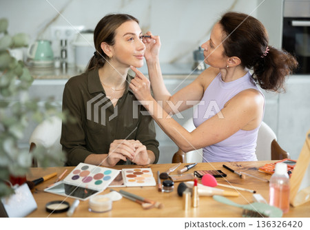 Adult woman doing makeup to young woman Adult woman doing makeup to young woman 136326420