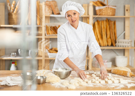 Woman works as baker in bakery, molds pies from dough, creates croissants from dough. Woman works as baker in bakery, molds pies from dough, creates croissants from dough. 136326522
