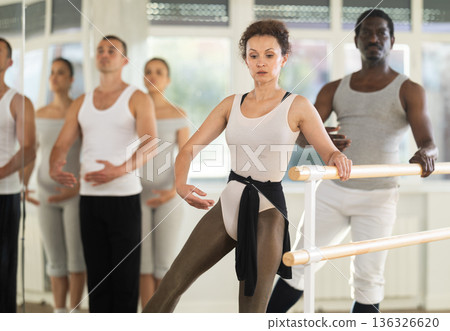 Woman and man dancers practicing batman tandu at barre 136326620
